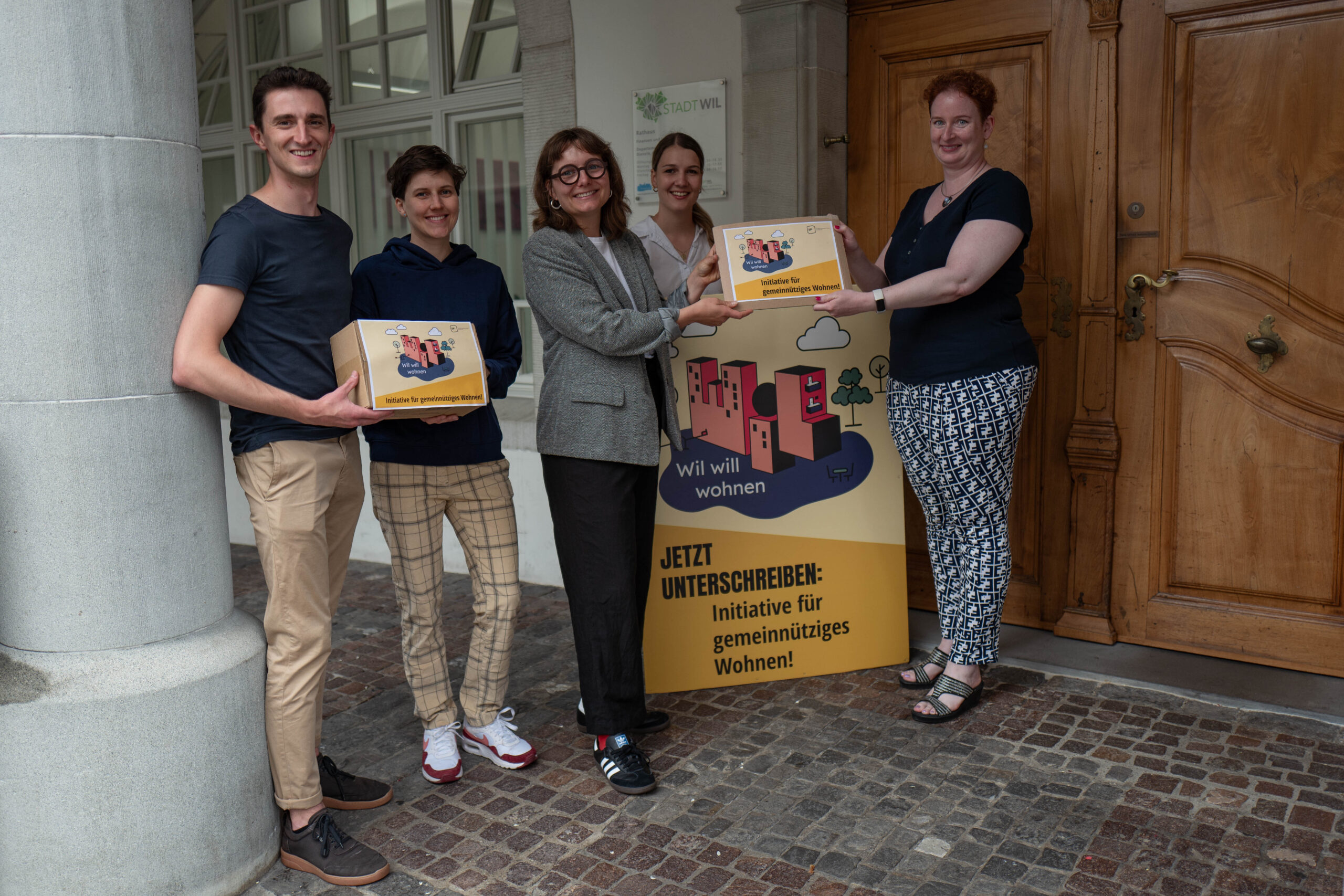 Das Initiativkomitee übergibt die beglaubigten Unterschriften der Stadtschreiberin vor dem Eingang des Rathauses.